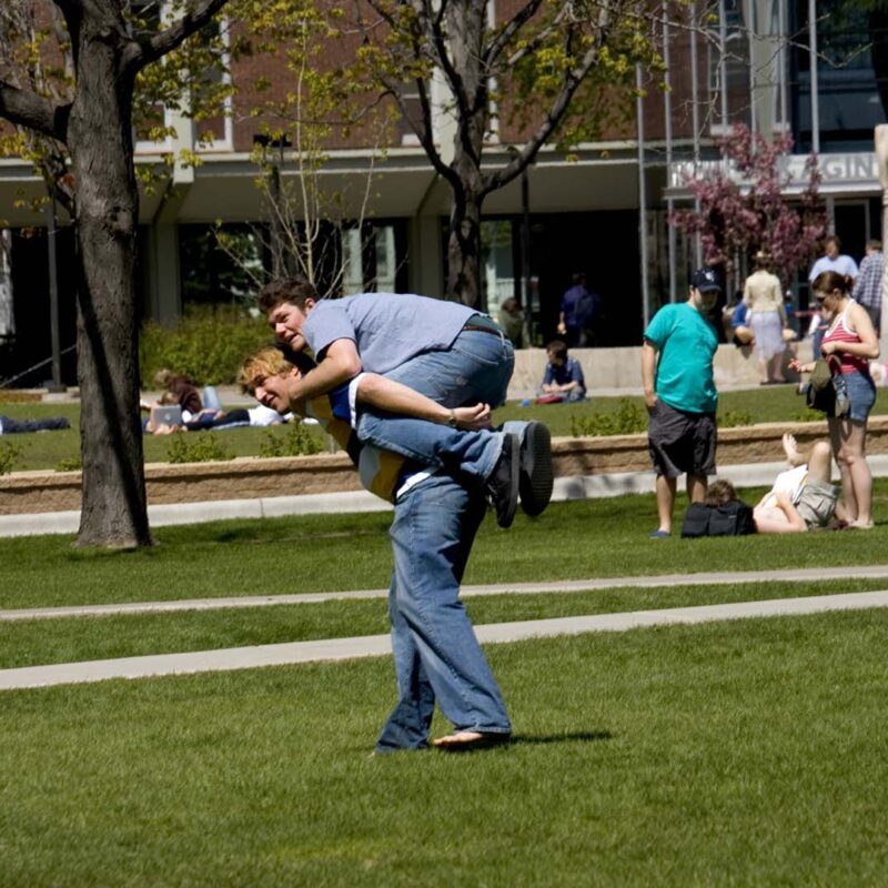 Student carrying another student on his back across campus